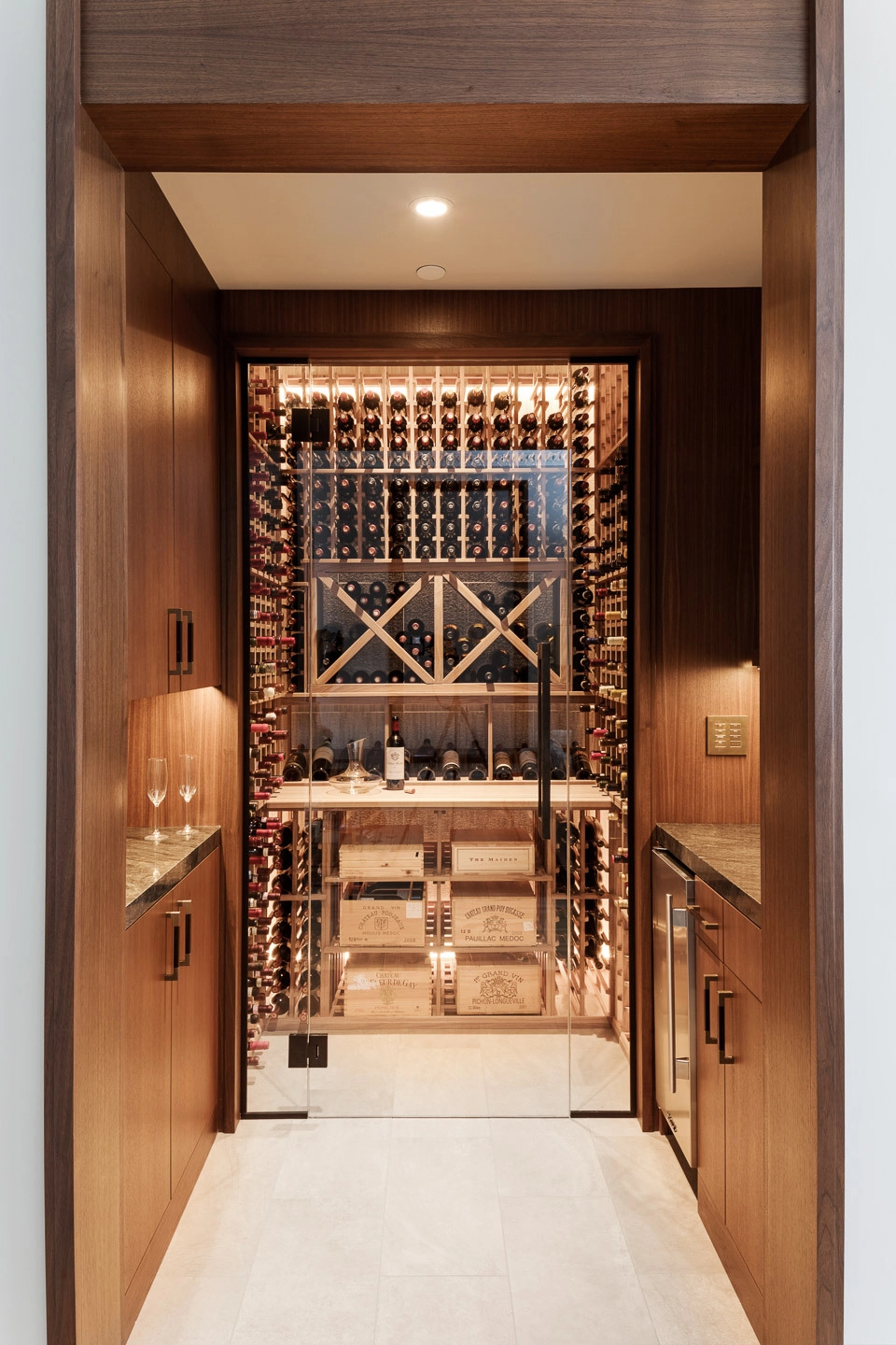 Bespoke Millwork and Trim - Custom walnut wine room with glass door and stone counters, Boston