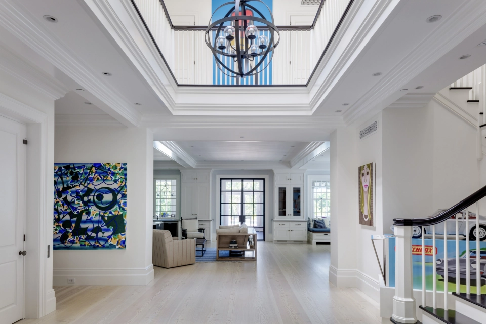 How We Build - Phase 4 - Two-story entry hall of a custom Cape Cod home with gallery walls